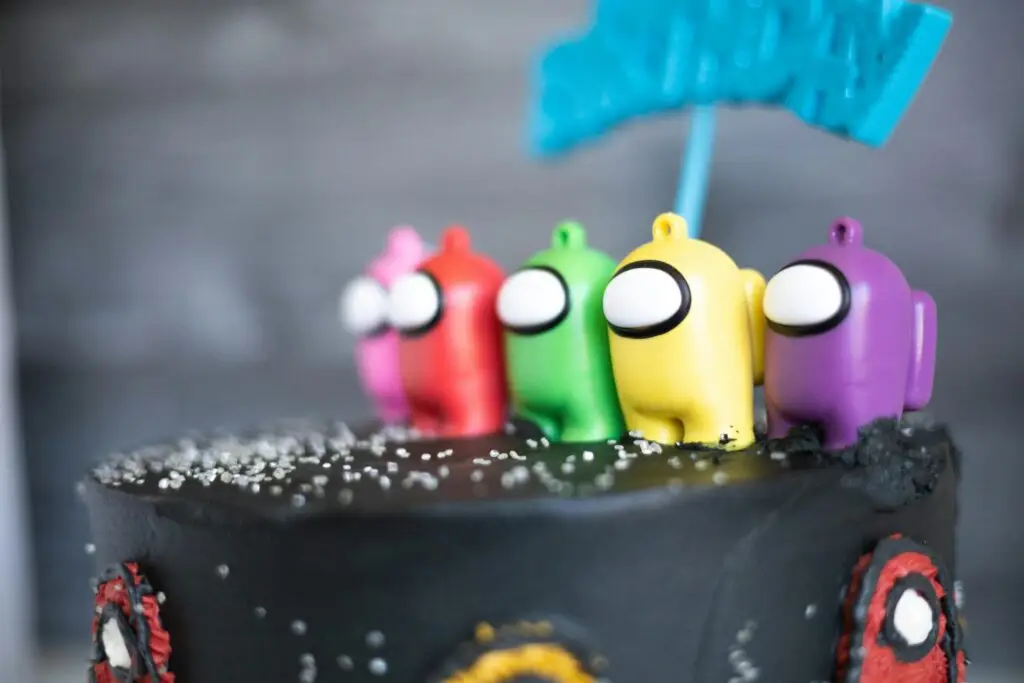Black cake with colorful toy figures as toppers, featuring a playful design.