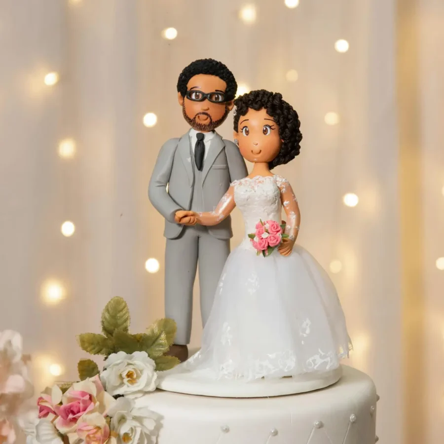 Cute bride and groom figurines on a beautifully designed wedding cake with floral decor.