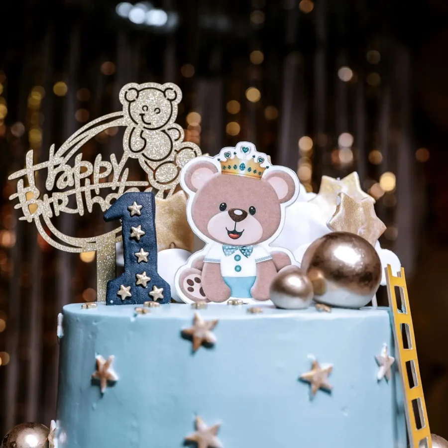 Adorable blue cake with teddy bear topper for a first birthday celebration, perfect for kids parties.
